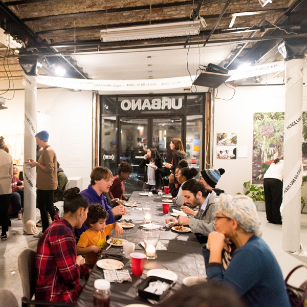 Various people sitting at a long table at Urbano, eating tortillas, and talking. Image by Faizal Westcott, courtesy of Urbano Project.
